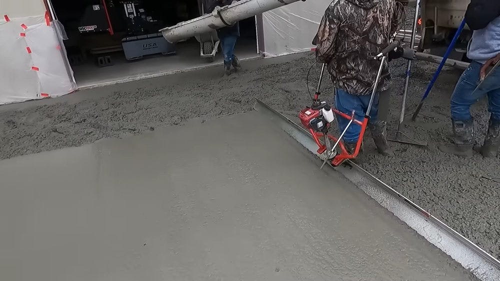 A man pouring concrete on driveway.