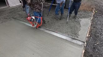 A concrete contractor working on wet concrete.